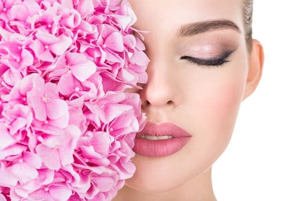 Clínica estética Madrid - Mujer de rostro perfecto con flores cubriendo parte de él luego de tratamientos estéticos en la mejor clínica estética Madrid