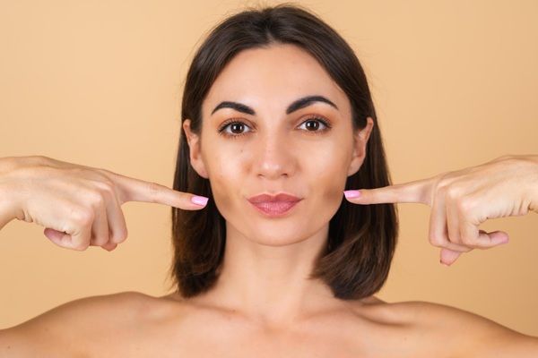 Mujer feliz luciendo un rostro perfecto y natural gracias a los tratamientos estéticos de rejuvenecimiento facial