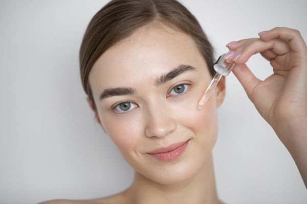 Ácido hialurónico Madrid - Chica joven aplicando gotas de ácido hialurónico Madrid en su piel para rejuvenecer el rostro