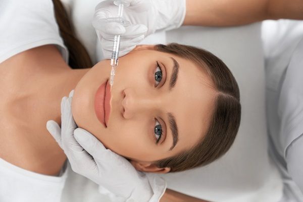 Ácido hialurónico Madrid - Médico estético aplicando ácido hialurónico Madrid en los labios de una mujer para dar volumen y conseguir una apariencia más joven