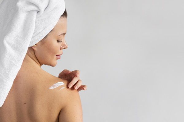 Mujer aplicando crema en la piel de su hombro