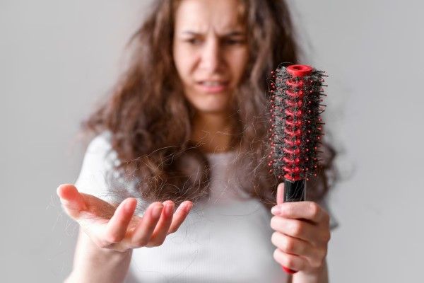 mujer mirando con preocupación el mechón de cabello en su mano por culpa de la alopecia
