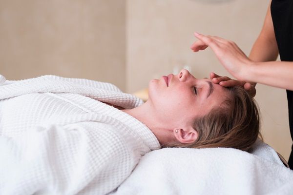Masajista aplicando una técnica de relajación a una mujer en el spa