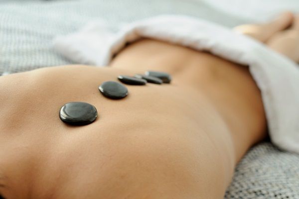 Mujer recibiendo un masaje con piedras calientes en la espalda