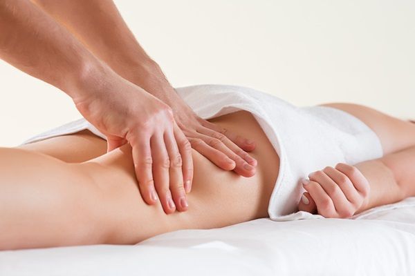 Masajes - Masajeador realizando un masaje anticelulitis en las piernas de una mujer