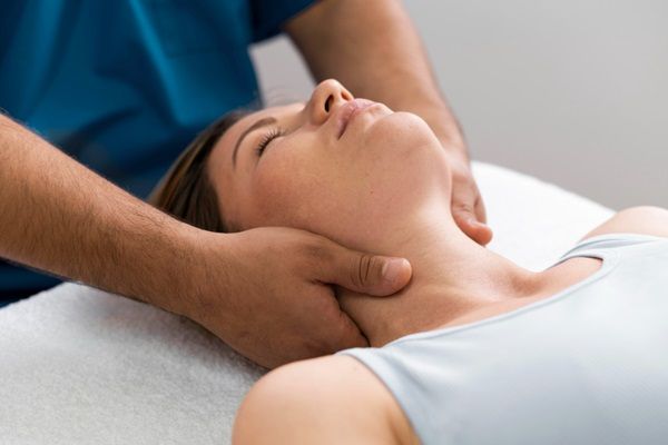 Masajes - Masajista realizando masajes relajantes en el cuello de una mujer joven