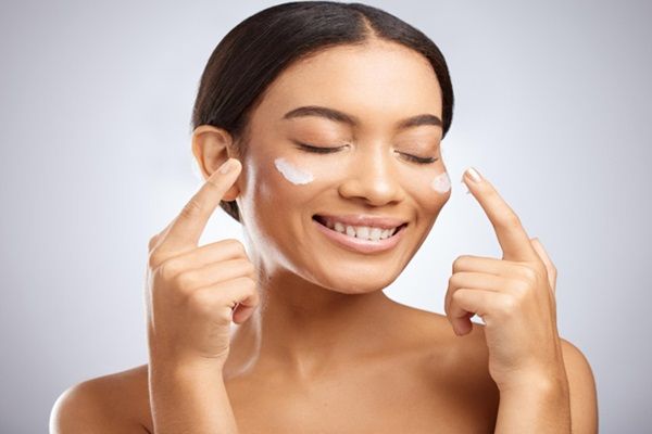Niacinamida - Mujer sonriente colocándose cremas con niacinamida en la cara