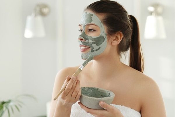 Mujer joven aplicándose una mascarilla facial, de los mejores remedios caseros para quitar las arrugas de la cara