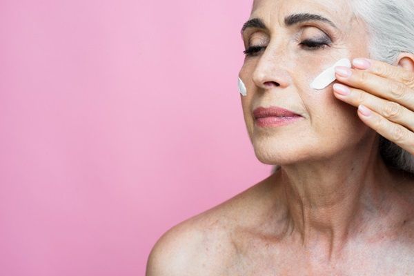 Mujer aplicándose crema arrugas en el rostro para hidratar la piel