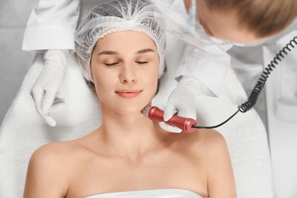 Aparatología estética - Médico especialista utilizando aparatología estética profesional en la piel de una mujer joven