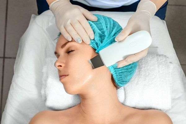 Mujer joven realizándose un tratamiento estético para limpiar la piel del rostro