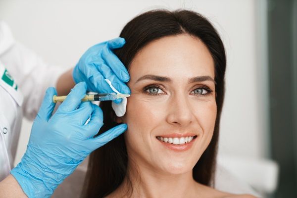 Médico realizando un tratamiento estético sin cirugía para rejuvenecer la piel de los párpados de una mujer