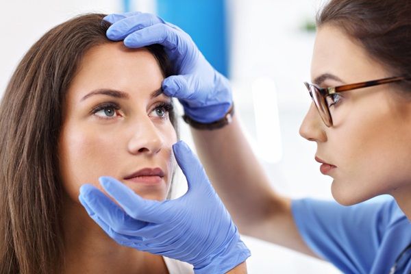 Blefaroplastia - Doctora realizando un examen ocular a una mujer joven para corregir problemas estéticos de los párpados