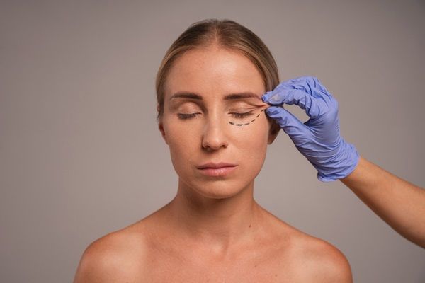 Blefaroplastia - Médico estirando la piel del párpado de una mujer para observar cómo queda la blefaroplastia antes y después