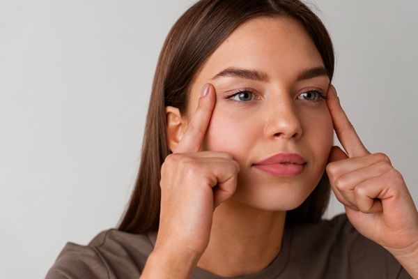 Blefaroplastia - Mujer joven estirando la piel de los párpados para observar cómo serían los resultados de la blefaroplastia sin cirugía