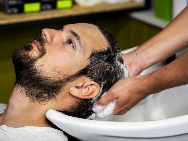Bótox capilar - Hombre sentado tranquilo mientras lavan su cabello luego de aplicar el botox capilar