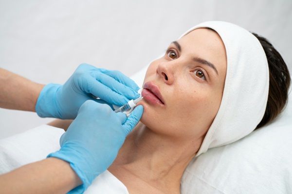 Médico estético realizando un tratamiento de aumento de labios a una mujer