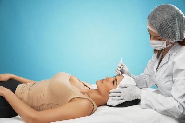 Tratamientos estéticos sin cirugía – Médico estético realizando un tratamiento de rejuvenecimiento facial a una mujer joven