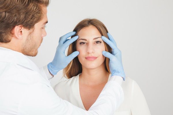 Médico estético evaluando la piel del rostro de una mujer durante una consulta en una de las mejores clínicas estéticas Madrid