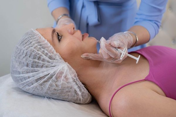 Tratamientos estéticos sin cirugía – Esteticista aplicando una inyección para realizar un tratamiento de aumento de labios a una mujer