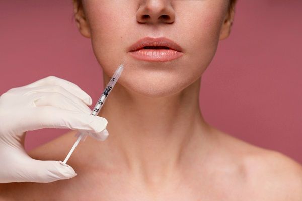 Tratamientos estéticos sin cirugía – Cirujano estético sujetando una inyectadora con ácido hialurónico para realizar un tratamiento de aumento de labios