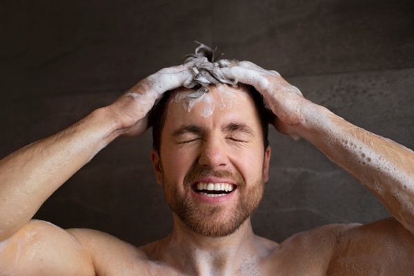 Champú post trasplante capilar - Hombre feliz aplicándose un Champú para injerto capilar que estimula el crecimiento de los folículos recién implantados