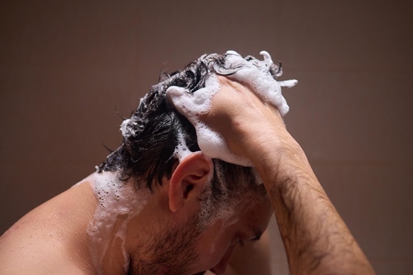 Hombre lavando su cabello con un producto capilar especial luego de un tratamiento de injerto capilar Madrid