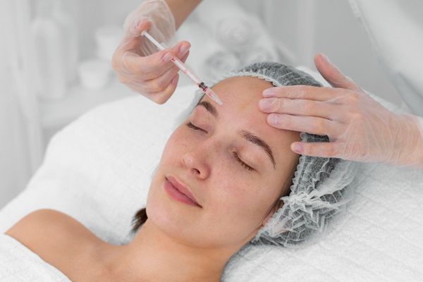 Tratamiento hidratación profunda - Esteticista realizando un tratamiento de hidratación profunda con acido hialuronico Madrid en el rostro de una mujer para eliminar las arrugas
