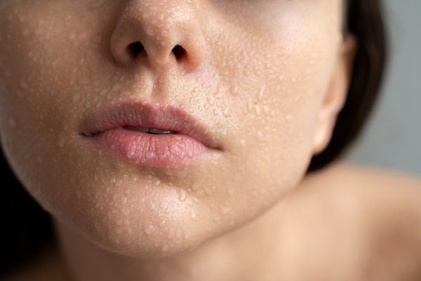 Mujer sudando por el exceso de calor que deshidrata y reseca la piel