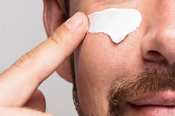 Hombre aplicando Cosméticos para tratamientos faciales y corporales, esta vez en su rostro