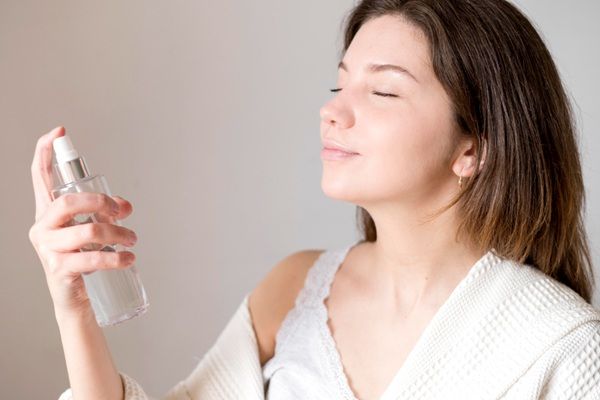 Bruma facial - Mujer aplicándose una bruma facial protector solar antes de salir para cuidar la piel del rostro de los rayos UV