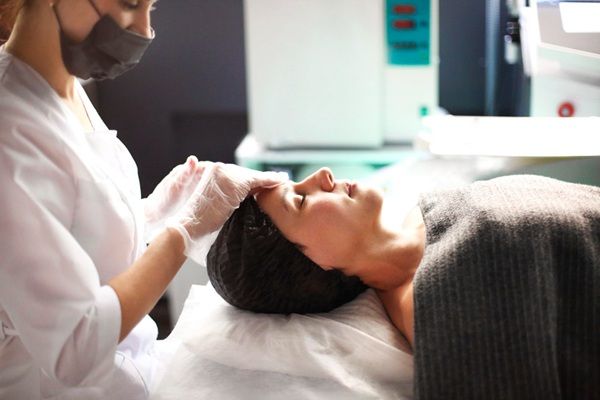 Terapias regenerativas - Médico estético aplicando un tratamiento de rejuvenecimiento facial a una mujer para promover la regeneración de tejidos