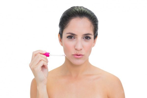 Relleno ácido hialurónico - Mujer aplicándose ácido hialurónico labios para hidratar y aumentar el volumen de los labios de manera natural