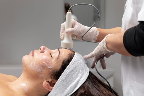 Esteticista profesional aplicando un tratamiento de rejuvenecimiento facial Barcelona a una mujer