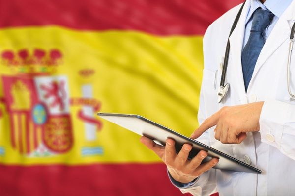 Turismo médico España - Médico tricólogo frente a una bandera de España donde se encuentra la mejor clínica injerto capilar España