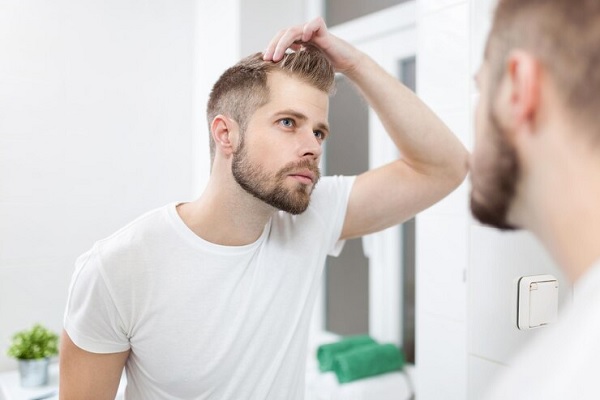 hombre revisando su cabello frente al espejo