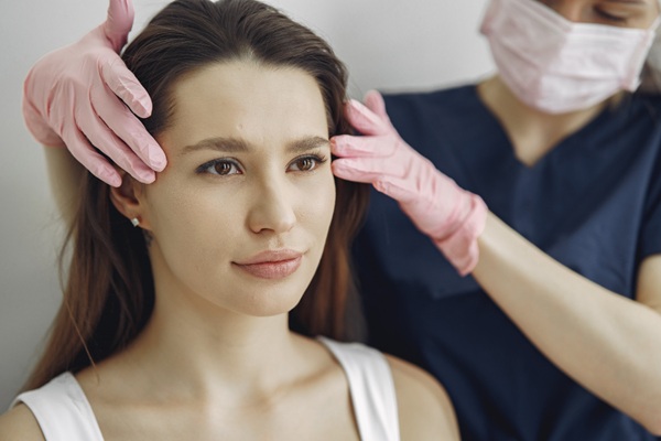 Médico estético evaluando el rostro de una mujer luego de un tratamiento de rejuvenecimiento para eliminar las arrugas dinámicas