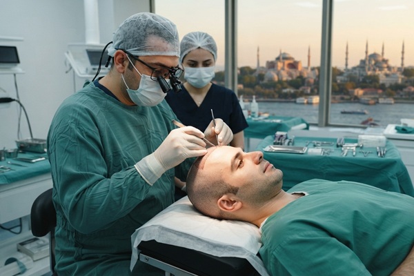 Cuánto cuesta un injerto capilar - Médico tricólogo realizando un injerto capilar Turquía a un hombre con alopecia en las entradas